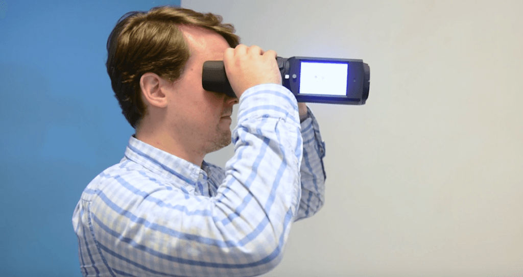 Un homme tient les binoculaires QuickSee devant ses yeux.